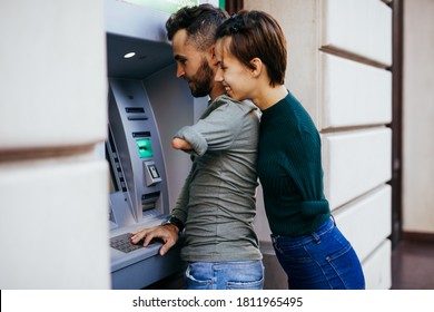 Disabled Couple Usinig ATM Machine In City Street.