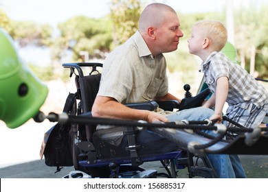 Disabled Father Play With His Little Son On The Playground