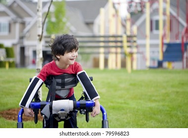 Disabled four year old boy standing in walker near a playground