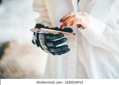 Disabled girl holding mobile phone with prosthesis arm. Close up hand with phone.