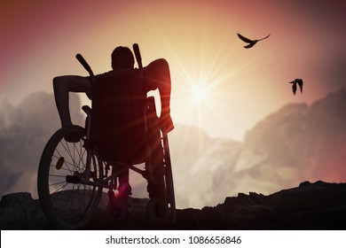 Behinderte Menschen mit Behinderungen haben Hoffnung. Er sitzt auf Rollstuhl und streckt sich bei Sonnenuntergang die Hände aus.