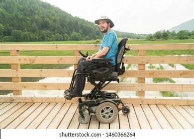 disabled happy young man in electric wheelchair on a boardwalk enjoying his freedom and smiling