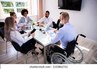 Disabled Male Manager Sitting With His Colleagues At Workplace