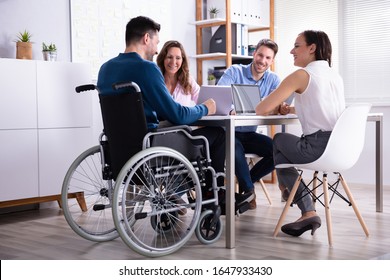 Disabled Male Manager Sitting With His Colleagues At Workplace