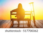 Disabled man has a hope on wheelchair of sunset background. Challenge and Conquer success and health care concept. Silhouette of person is sitting stretching hands out at sunset effects of war.