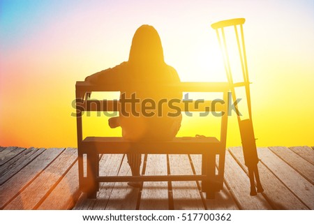 Disabled man has a hope on wheelchair of sunset background. Challenge and Conquer success and health care concept. Silhouette of person is sitting stretching hands out at sunset effects of war.