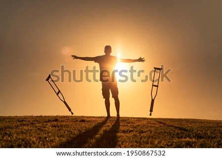 A disabled man letting go of his crutches facing the sunset. Healing medical concept of cure, recovery, miracle, hope, insurance