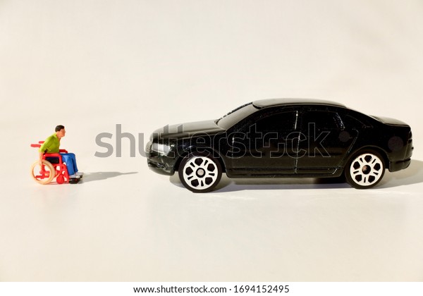 disabled man on\
a wheelchair and car in miniature\
