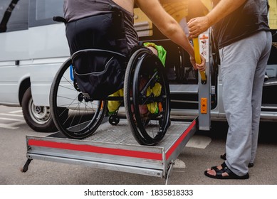 Disabled man on wheelchair using accessible vehicle with lift mechanism.