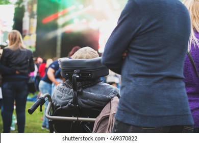 Disabled Man In A Special Needs Wheelchair Watching A Conecrt At A Festival