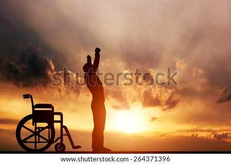 A disabled man standing up from wheelchair at sunset. Positive concept of cure, recovery, medical miracle, hope, insurance etc. 