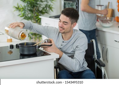 disabled man tipping pasta into saucepan on hob