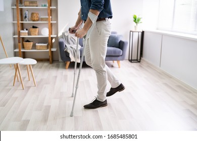 Disabled Man Using Crutches To Walk At Home