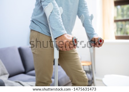 Disabled Man Using Crutches To Walk At Home