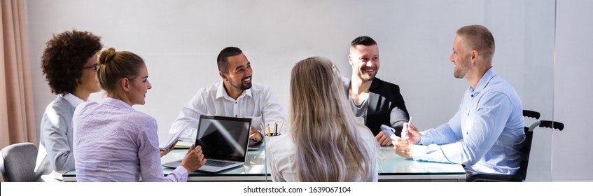 Disabled Manager Sitting With His Colleagues At Workplace