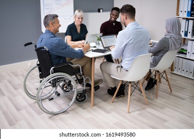 Disabled Mature Businessman Sitting At Desk With Laptop In Conference Room - Shutterstock ID 1619493580