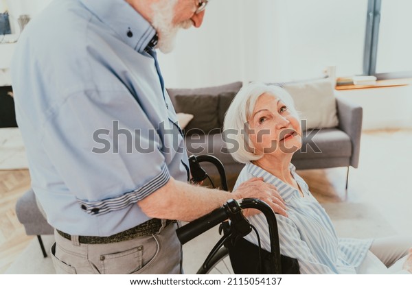 Disabled old woman on\
wheel chair - Senior couple at home, partner coming back from\
hospital in\
convalescence