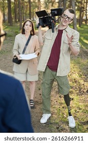 Disabled operator with camera talking to man during outdoor video shooting
