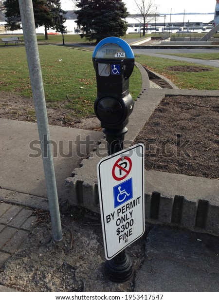 Disabled parking permit sign (300\
Canadian dollar fine) and parking meter in Kingston,\
Canada.