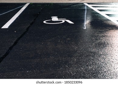 Disabled Parking Sign Painted On Dark Asphalt At Night