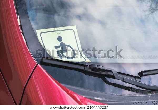 Disabled person driving sign on the windshield\
of a car. Identification symbol confirming the right of disabled\
car owners to benefits