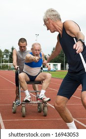 Disabled Person And His Helper Reaching For An Other Athlete To Pass Him The Baton. Caricature Picture To Illustrate Helping, Giving, Disabilty, Ability, Getting Older, Not Wanna Quit.