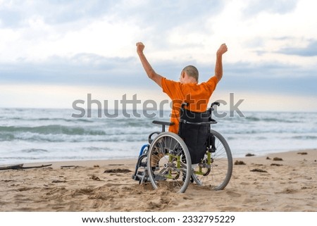 Disabled person on his back in a wheelchair on the beach with open arms enjoying the freedom