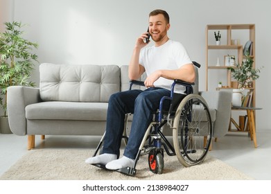 The disabled person sits in a wheelchair. He is talking to someone on his smartphone. He is in his large bright living room. He smiles. - Powered by Shutterstock