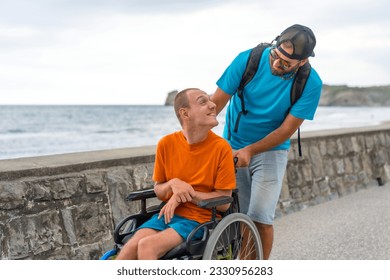 Disabled person in a wheelchair being pushed by a friend on the beach promenade, having fun in summer - Powered by Shutterstock