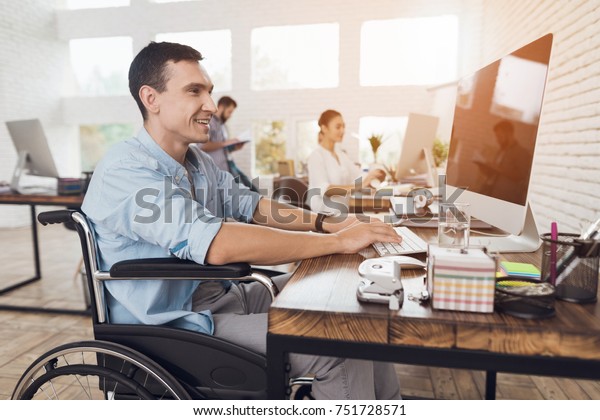 Disabled\
person in the wheelchair works in the office at the computer. He is\
smiling and passionate about the\
workflow.