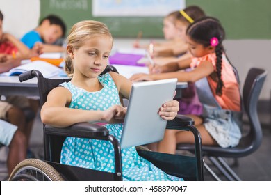 Disabled schoolgirl using digital tablet in classroom at school - Powered by Shutterstock