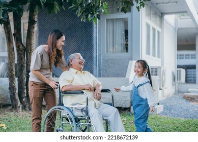 Disabled Senior Grandpa On Wheelchair With Grandchild And Mother In Park, Happy Asian Multi Generation Family Having Fun Together Outdoors Backyard, Grandpa Elderly And Little Child Smiling And Laugh.