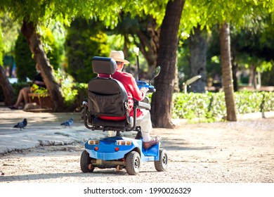Disabled senior man using electric wheelchair in the park. Lifestyle and independence of disabled people