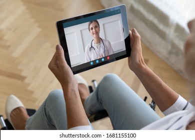 Disabled Senior Woman Sit In Wheelchair Hold Tablet Talk With Young Woman Doctor Using Wireless Internet Connection, Handicapped Mature Old Lady Speak Consult With Medical Specialist On Pad