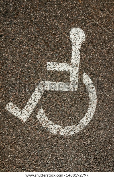 Disabled symbol sign on asphalt in\
parking space. International markings for a handicapped\
parking.