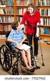 Disabled Teen With Forearm Crutches, Talking To A Little Boy In A Wheelchair.  They Are In The Library.