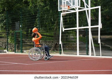 Disabled teenage boy in wheelchair playing basketball  on outdoor court - Powered by Shutterstock