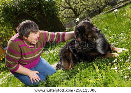 disabled woman on a lawn is stroking a dog