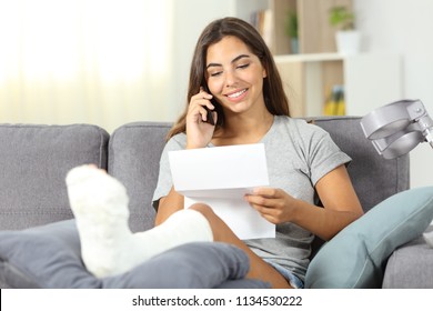 Disabled Woman On The Phone Reading A Letter Sitting On A Couch In The Living Room At Home