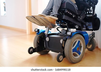 A disabled woman sitting in a blue electric wheelchair indoors