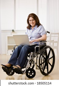 Disabled Woman Sitting In Wheel Chair Typing On Laptop