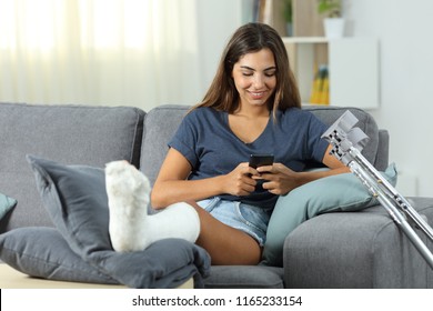 Disabled woman using a smart phone sitting on a couch in the living room at home - Powered by Shutterstock