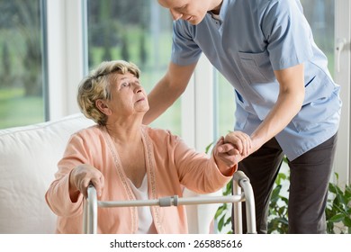 Disabled woman using walker assisted by physiotherapist