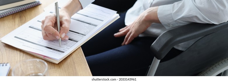 Disabled woman in wheelchair filling out application for employment closeup