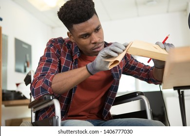 Disabled Worker In Wheelchair Sanding Wood Indoors