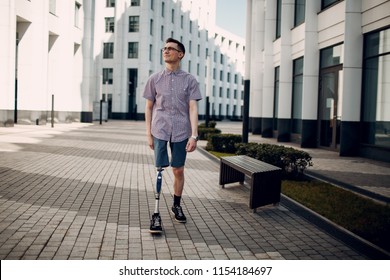 Disabled Young Man With Foot Prosthesis Walks Along The Street.