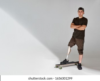 Disabled young man with leg prosthesis with longboard skateboard on white background. Sun light. - Powered by Shutterstock