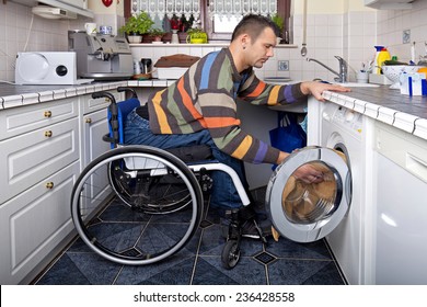 Disabled young man in wheelchair washing clothes
