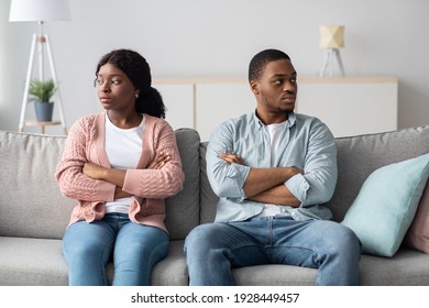 Disappointed african american couple young man and woman with arms crossed on chest having relationships crisis, sitting on couch and looking aside, do not talking to each other after fight