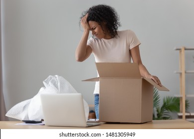 Disappointed African American Millennial Girl Unpacking Cardboard Delivery Box Frustrated By Delivered Product, Upset Confused Black Young Woman Shopping Online Unwrap Open Bad Quality Product